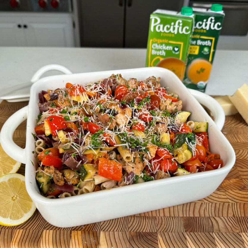An image of prepared Gluten-Free Sheet Pan Honey Dijon Pasta made with zucchini, red onions, cherry tomatoes, chicken thigh, Pacific Foods® Free Range Chicken Broth and gluten free pasta.