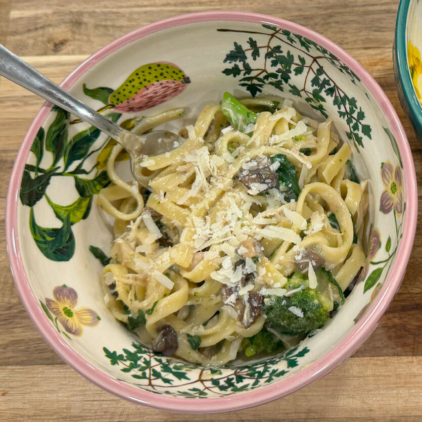 An image of prepared Sunday Night Creamy Mushroom Pasta made with pasta, mushrooms, chicken, Pacific Foods® Organic Cream of Mushroom Condensed Soup, Pacific Foods® Free Range Chicken Broth, spinach, broccoli and Parmesan cheese.