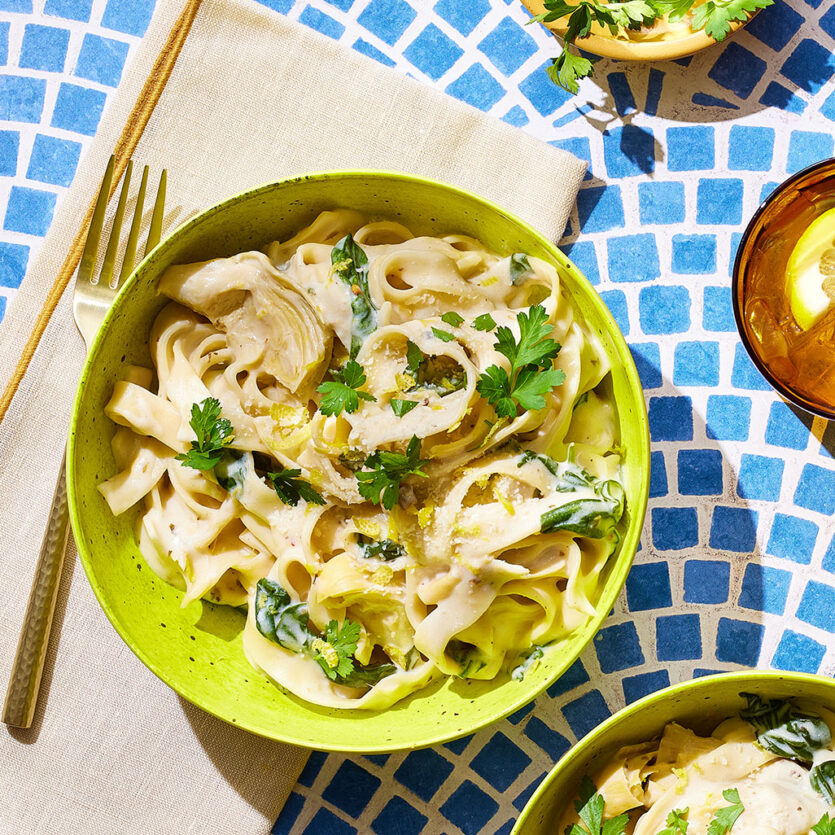 An image of prepared Creamy Spinach and Artichoke Dip Pasta made with pasta, garlic, baby spinach, artichoke hearts, Pacific Foods® Organic Cream of Mushroom Condensed Soup, cream cheese and Parmesan.