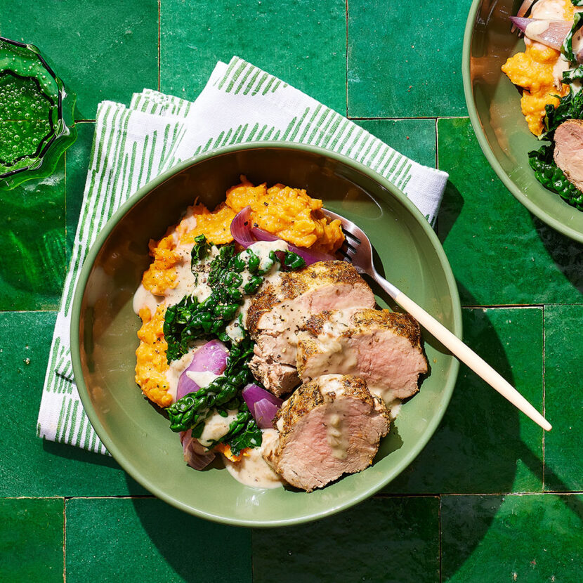 An image of prepared Garlic Herb Pork Tenderloin with Creamy Sweet Potato Mash made with sweet potatoes, pork tenderloin, onion Tuscan kale, Pacific Foods Condensed Cream of Roasted Garlic & Herb Soup and Pacific Foods® Organic Low Sodium Free Range Chicken Broth.
