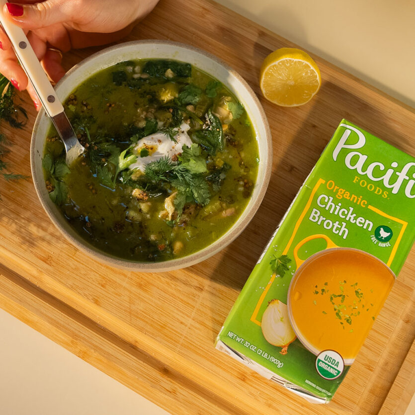 An image of prepared Green Chicken Soup with Chickpeas and Sizzled Coriander made with leeks, onions, spinach, cilantro, garbanzo beans, Pacific Foods® Chicken Broth and chicken thighs.