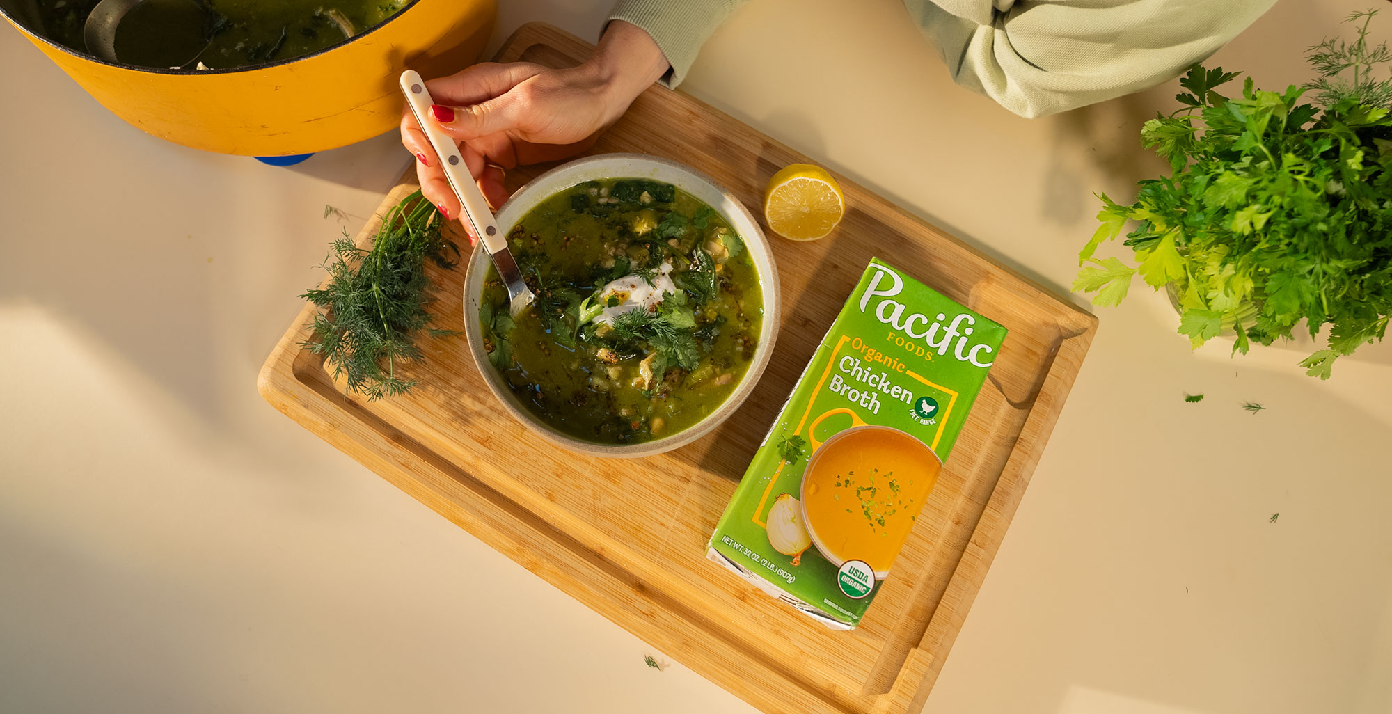 An image of prepared Green Chicken Soup with Chickpeas and Sizzled Coriander made with leeks, onions, spinach, cilantro, garbanzo beans, Pacific Foods® Chicken Broth and chicken thighs.
