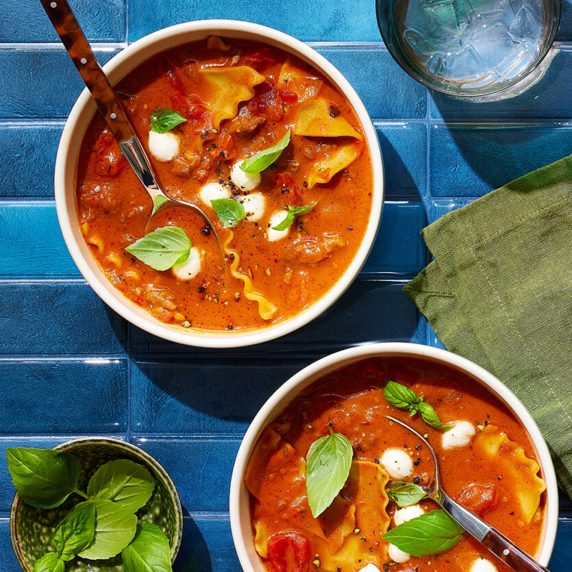 An image of prepared Hearty Lasagna Soup with Red Wine and Fresh Mozzarella made with yellow onion, tomato paste, garlic, Italian pork sausage, Pacific Foods® Organic Vegetable Broth, Pacific Foods™ Organic Cream Tomato Basil Soup, canned diced tomatoes, lasagna noodles, fresh mozzarella and basil.