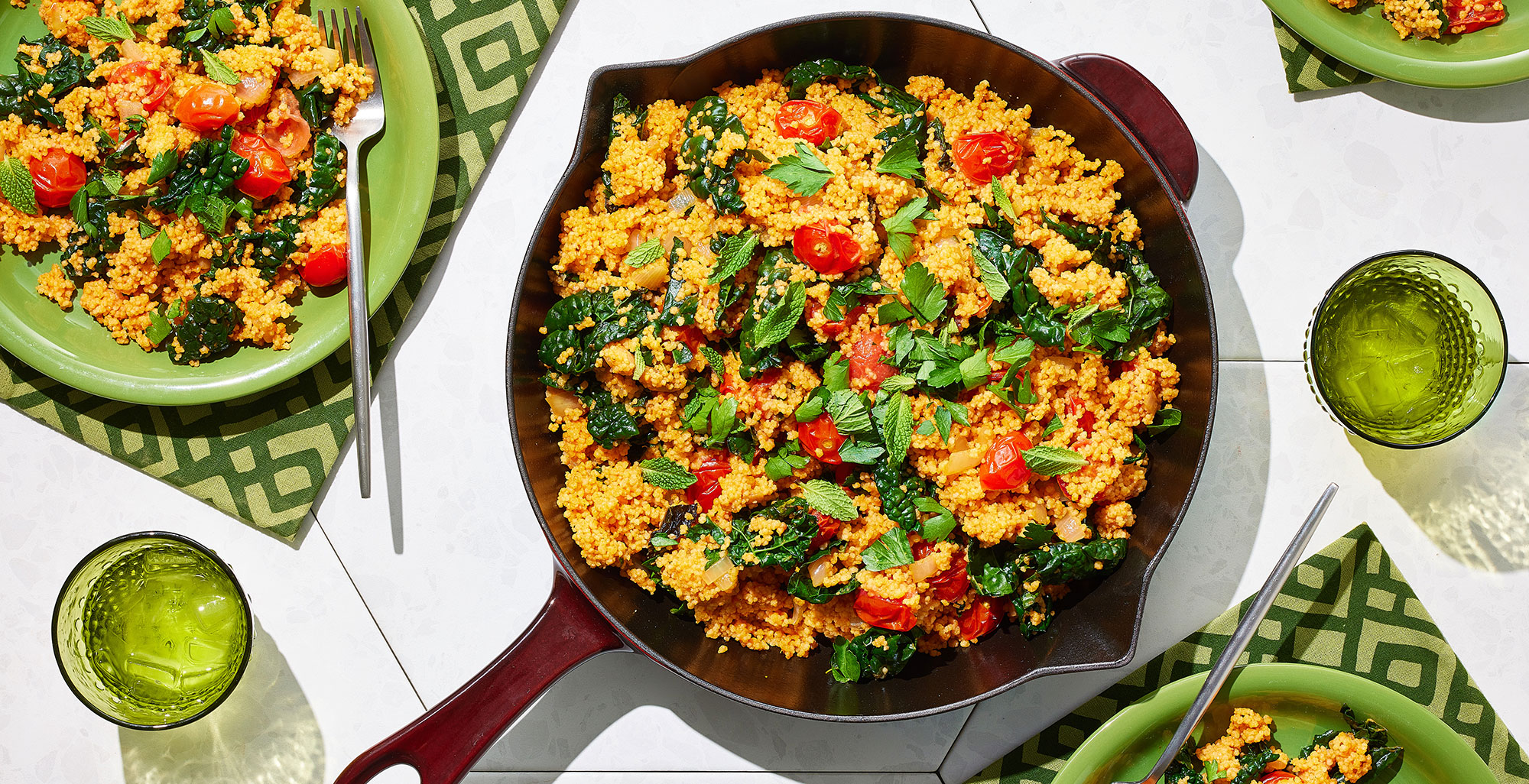 An image of prepared Roasted Red Pepper Couscous with Garlicky Tomatoes, Onions and Kale made with garlic, red bell pepper, Pacific Foods® Organic Low Sodium Vegetable Broth, couscous, Pacific Foods® Organic Roasted Red Pepper & Tomato Soup, grape tomatoes, kale, parsley and mint.