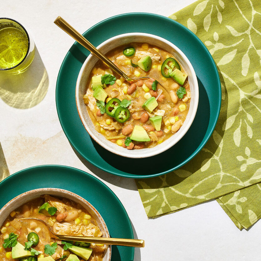 An image of prepared White Turkey Chili with Corn made with cumin, chili powder, turkey tenderloin, onion, corn, Pacific Foods® Organic Turkey Broth, pinto beans, green chiles and corn tortillas.