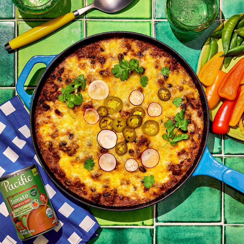 An image of prepared Beef Enchilada Dip made with ground beef, taco seasoning, garlic, Pacific Foods® Organic Condensed Tomato Soup, black beans, cream cheese and Mexican blend cheese.