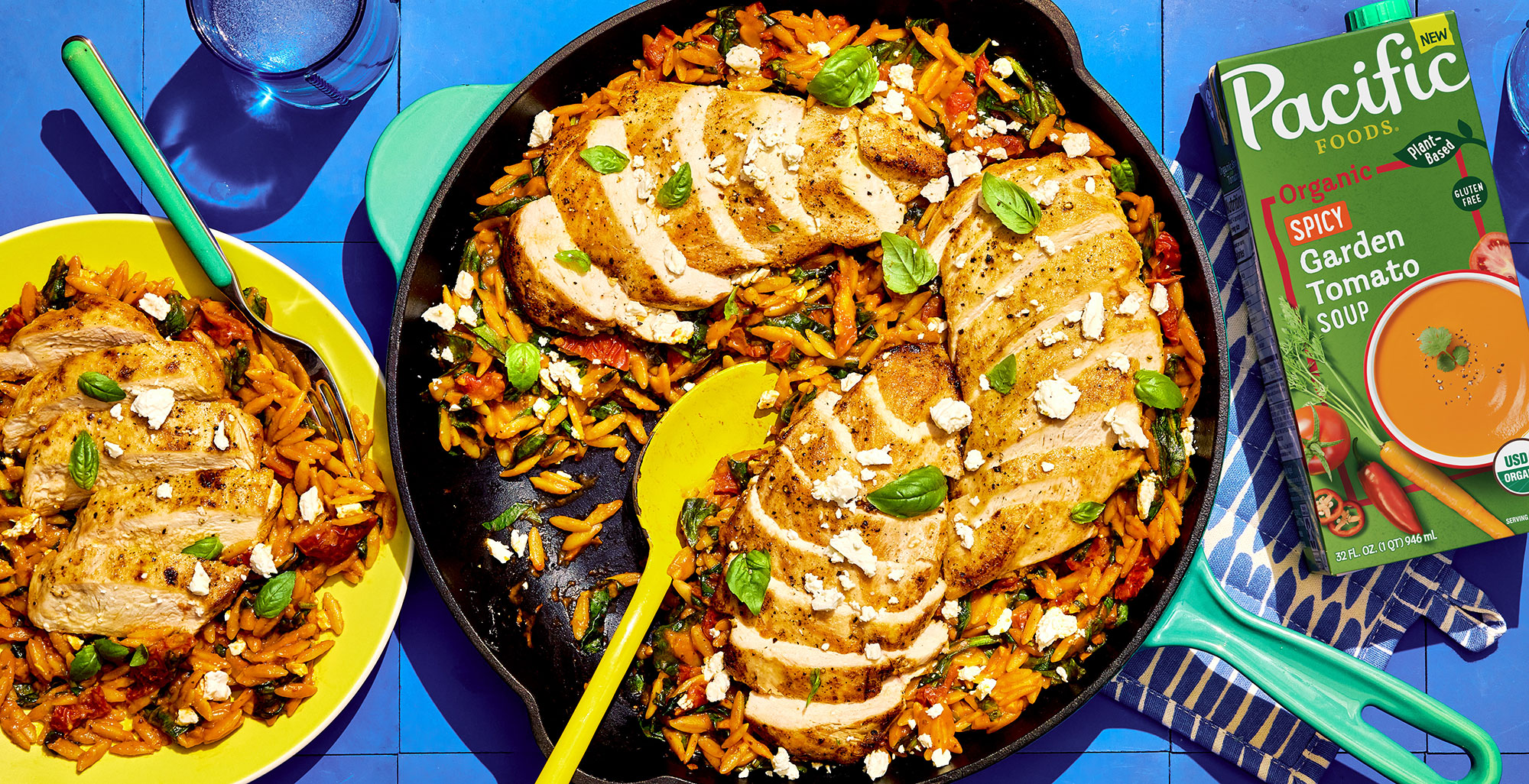 An image of prepared Skillet Tuscan Chicken with Orzo made with chicken, sun-dried tomatoes in olive oil, garlic, orzo pasta, white wine, Pacific Foods® Organic Spicy Garden Tomato Soup, baby spinach, feta cheese and basil.