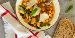 An image of prepared Summer Beans Stew made with Roma tomatoes, butter beans, chickpeas, Pacific Foods® Organic Vegetable Broth and basil.