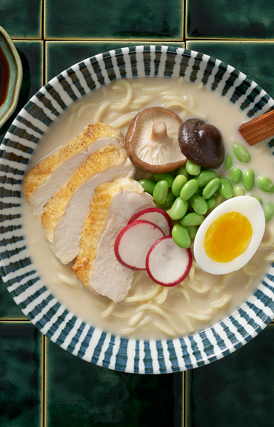An image of prepared Chicken Miso Ramen made with eggs, ramen noodles, Pacific Foods® Organic Chicken Miso Ramen Broth, chicken, edamame, corn, green onion and radish.