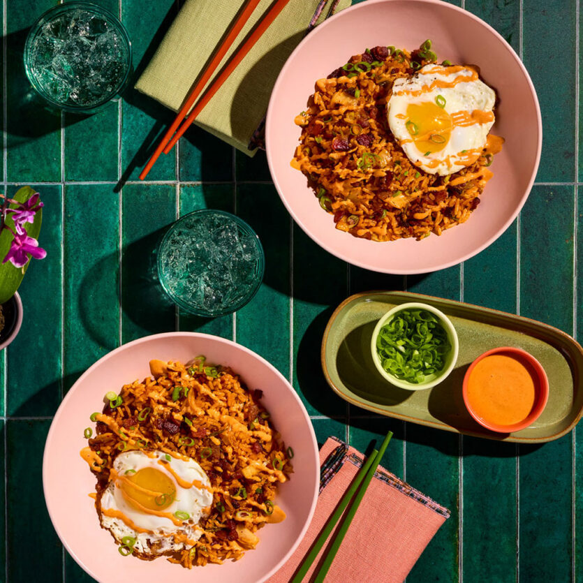 An image of prepared Kimchi Fried Rice with Fried Eggs and Gochujang Mayo made with Pacific Foods® Organic Pork Tonkotsu Ramen Broth, white rice, bacon, kimchi, gochujang and mayonnaise.