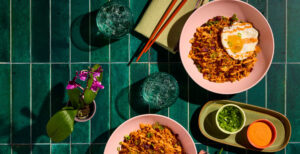An image of prepared Kimchi Fried Rice with Fried Eggs and Gochujang Mayo made with Pacific Foods® Organic Pork Tonkotsu Ramen Broth, white rice, bacon, kimchi, gochujang and mayonnaise.